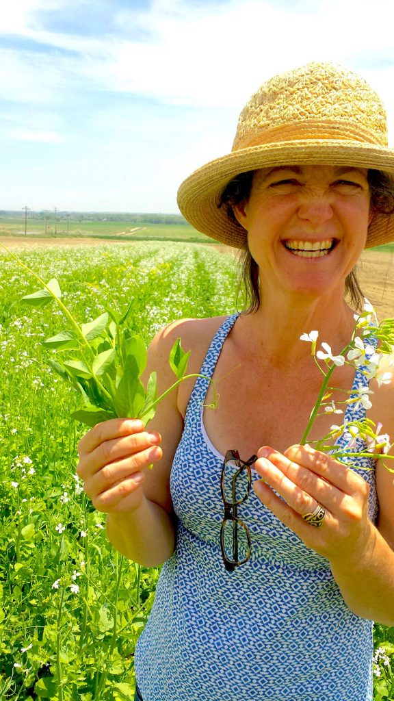 Jill holding daikon radish and Austrian field peas, both of which are cover crops — and delicious.