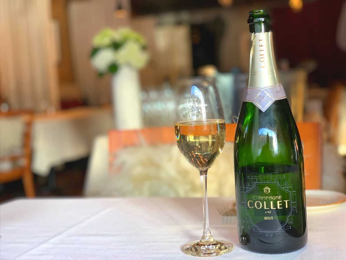 A bottle of Collet Champagne with a flute of Champagne on a table at Black Cat Bistro